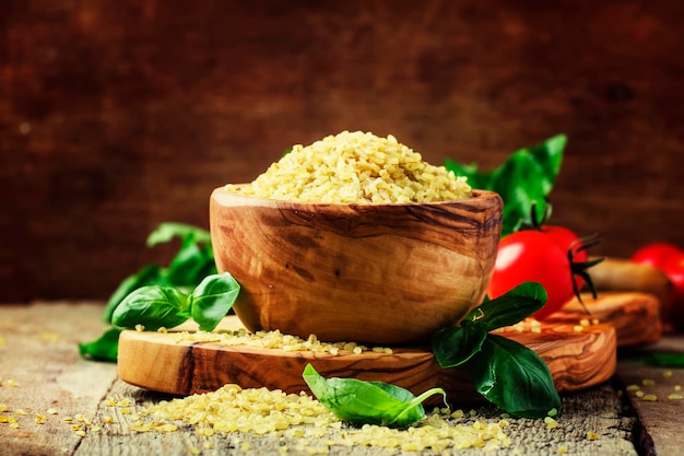 Bulgur d'orzo crudo in un fuoco selettivo del fondo dell'annata della ciotola di legno