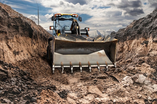 Bulldozer o caricatore che lavora in trincea Potente pala gommata o bulldozer con una grande benna in un cantiere edile Noleggio di attrezzature edili