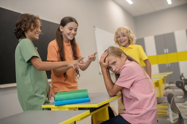 Bullismo. Una ragazza in maglietta rosa che soffre di bullismo dei compagni di classe