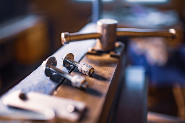 Bulloni e dadi in metallo cromato su macchina massiccia flessibile manuale. Vecchia classica pressa per costruzione meccanica di parti di macchine vintage retrò per la lavorazione di lamiera d'acciaio