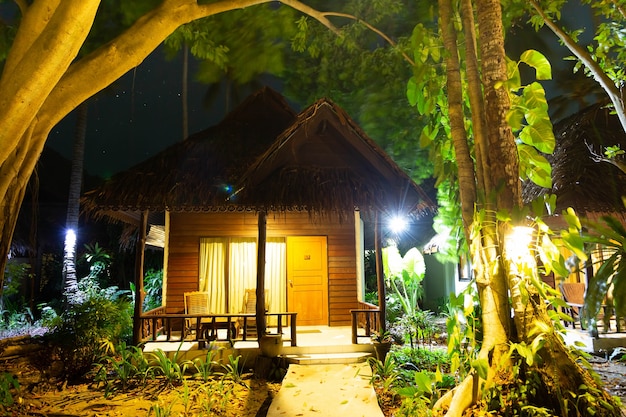 Bungalow in legno nella foresta Casa di notte nella giungla Alti alberi tropicali verdi