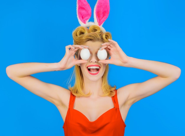 Bunny girl con uova bianche. Buona Pasqua. Donna divertente nelle orecchie di coniglio. Decorare l'uovo.