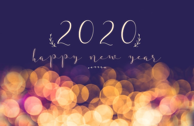 Buon anno 2020 della scrittura a mano sul fondo festivo della luce del bokeh della sfuocatura d'annata