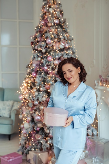 Buon anno! bella giovane donna con regali in mano vicino all'albero di Natale