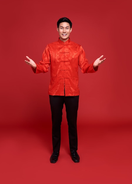 Buon Capodanno cinese. Bell'uomo asiatico con il gesto della mano aperta di introdurre isolato su sfondo rosso.
