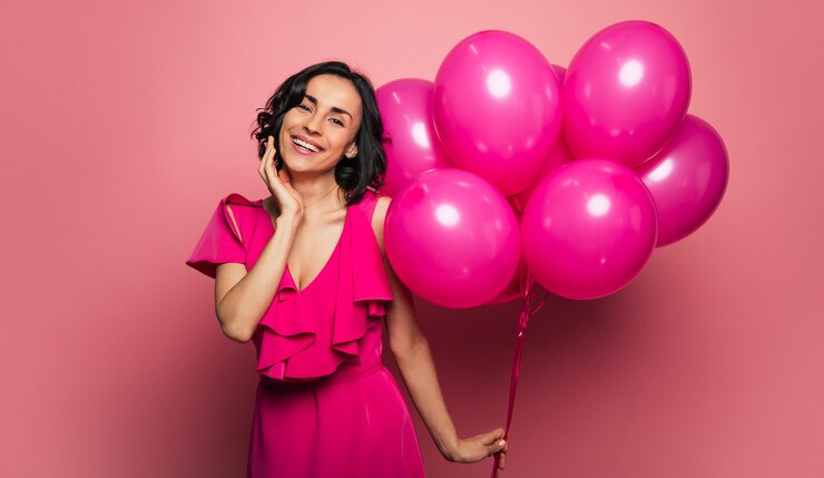 Foto buon compleanno a me! la giovane donna adulta in un abito festivo tiene un mazzo di palloncini nella mano sinistra e sorride ampiamente, mentre festeggia il suo compleanno.