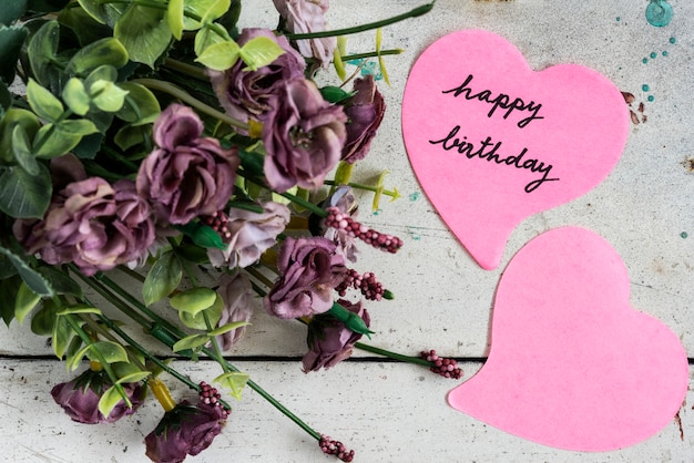 Buon compleanno nota in carta a forma di cuore con fiori viola