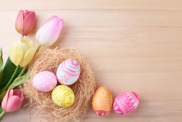 Buon giorno di Pasqua uova nel nido e fiori su fondo di legno con spazio di copia