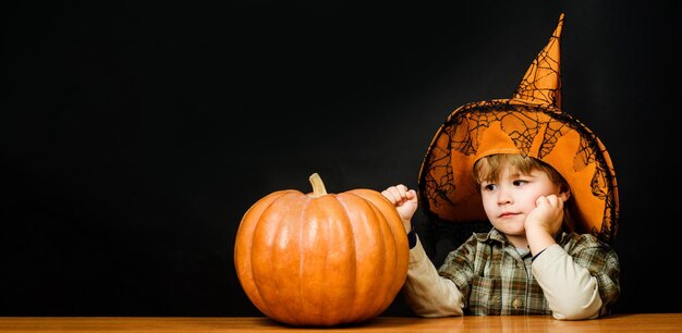 Buon Halloween, carino ragazzino con il cappello da strega con la zucca di Halloween, piccolo mago con