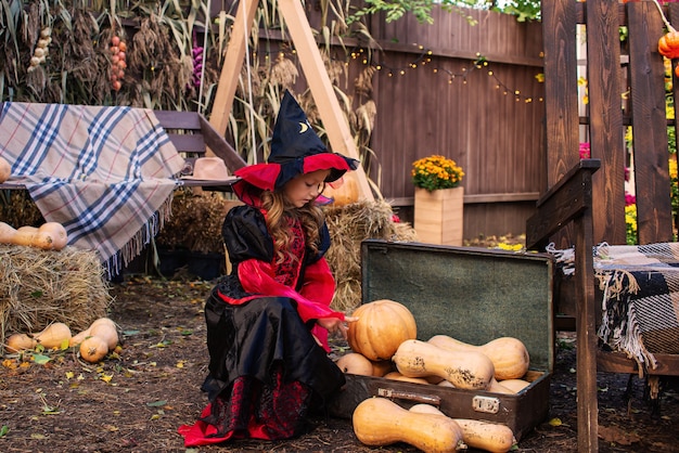 buon Halloween una ragazza in costume da strega con una zucca che si diverte in autunno vicino alla casa