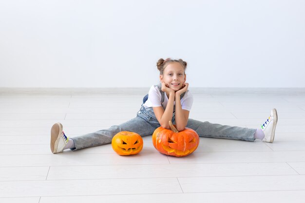 Buon Halloween, vacanze autunnali e concetto di infanzia - Bambina carina con una zucca Jack-o'-lantern al chiuso.