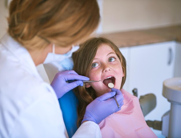 Buon lavoro con un'ampia apertura Inquadratura ritagliata di un dentista che esamina i denti di una bambina