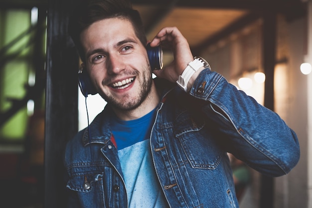 Buon lavoro e buona musica. Giovane allegro in cuffie che ascolta la musica mentre si siede al suo posto di lavoro