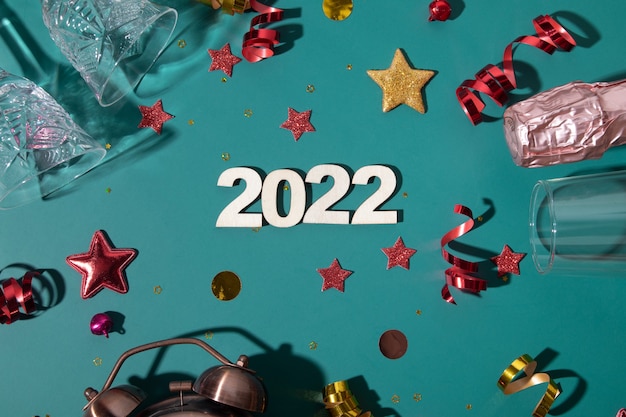 Buon Natale capodanno 2022 numero piatto con champagne, vetro e sveglia, stelle, stelle filanti su sfondo verde