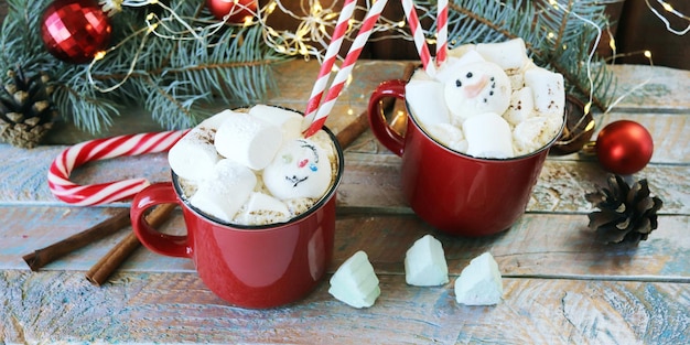 Buon Natale due tazze di caffè rosse con marshmallow rami di abete rosso giocattoli di Capodanno