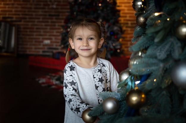 Buon Natale e Buone Feste. Carino bambina e ragazzo sta decorando l'albero di Natale al chiuso.