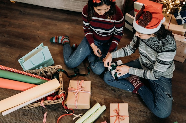 Buon Natale e buone feste! giovani donne che fanno opere d'arte tagliando il nastro sulla confezione regalo a casa. ragazza con le forbici della holding dei cervi.