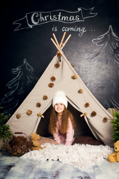 Buon Natale e buone feste. Infanzia felice. Ragazza che posa nelle decorazioni di natale.