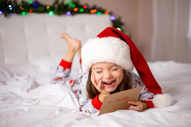 Buon Natale e buone feste La bambina felice sul letto ha scritto una lettera a Babbo Natale