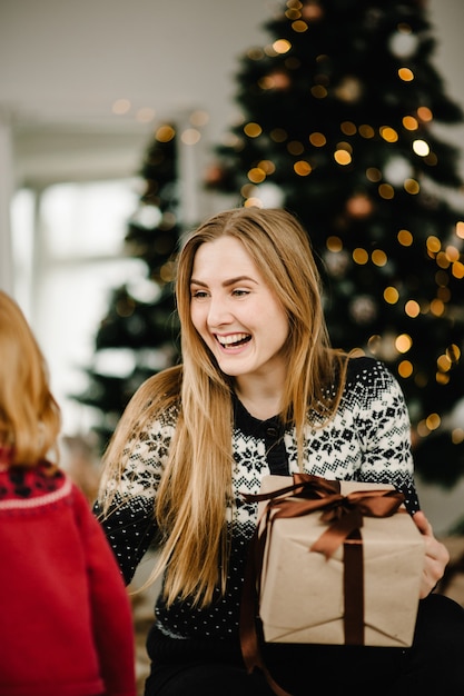 Buon Natale e buone feste La mamma fa un regalo a sua figlia vicino all'albero di Natale