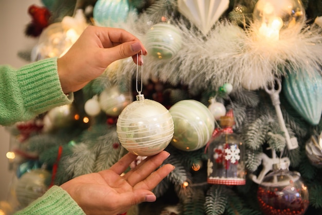 Buon Natale e Buone Feste. La ragazza sta decorando l'albero di Natale all'interno