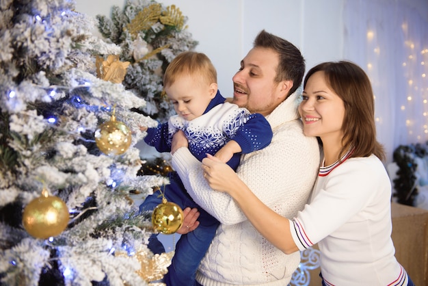 Buon Natale e Buone Feste. Mamma, papà e figlio allegri che scambiano i regali.