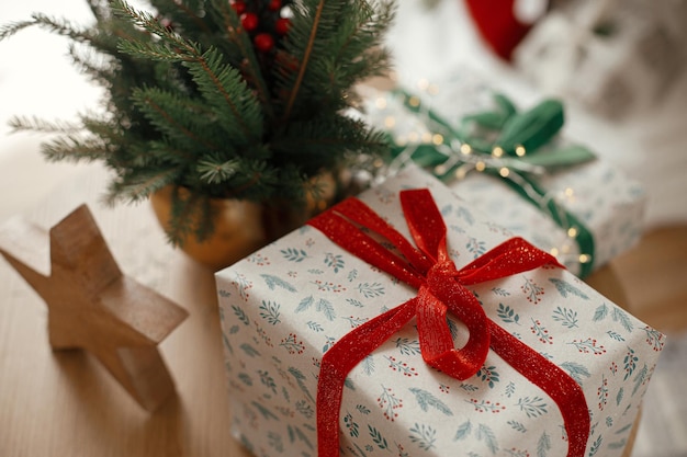 Buon Natale e buone vacanze regali di Natale arrotolati in stile stella di legno e rami di abete con bacche rosse sul tavolo in una sala scandinava festiva Immagine atmosferica