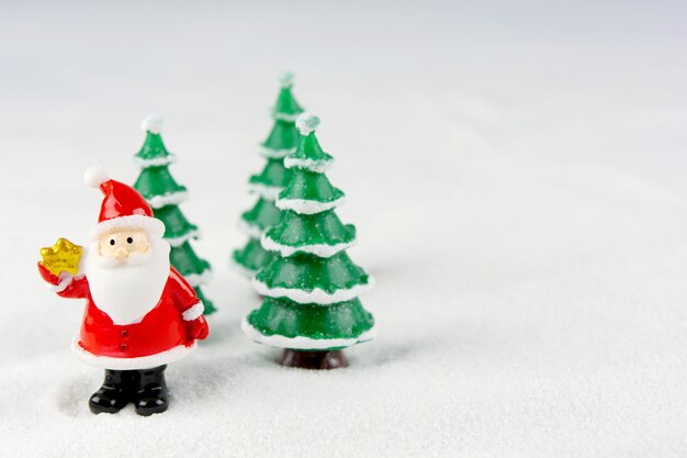 Buon Natale e felice anno nuovo concetto. Figura sveglia del Babbo Natale e albero sulla neve con lo spazio della copia