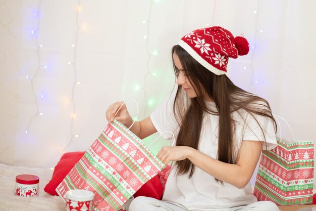 Buon Natale e Felice Anno nuovo. Una giovane donna guarda in una tasca con i regali