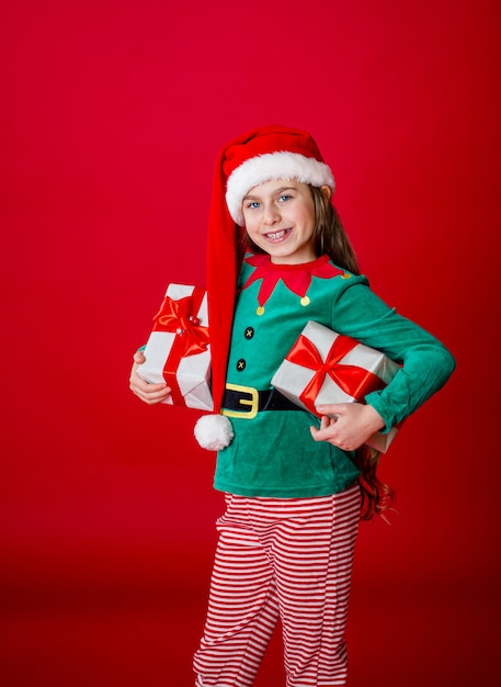 Buon Natale, felice ragazza attraente con doni in un costume di Babbo Natale elfo aiutante