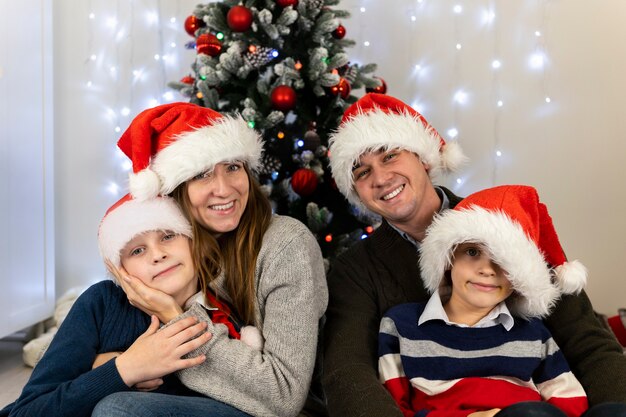 Buon Natale in famiglia insieme: mamma papà i bambini si abbracciano e sorridono.