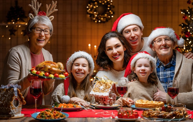 Buon Natale! La famiglia felice sta cenando a casa. Festa di celebrazione e solidarietà vicino all'albero.