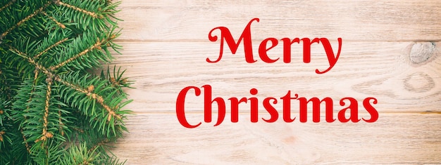 Buon Natale testo Natale vintage banner dai toni arancione sullo sfondo di legno con abete e copia spazio vista dall'alto lo spazio vuoto per il tuo design