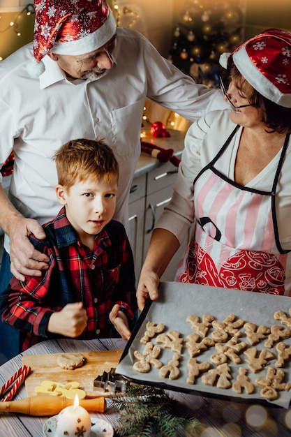 Buon natale tradizione bambino ragazzo che prepara il pan di zenzero in cucina con i nonni