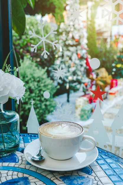 Buon NataleLatte caldo al caffè con schiuma di latte latte art in tazza tazza con decorazioni natalizie e palline dell'albero di Natale sulla scrivania del pavimento in marmo Festeggiamo Buon Natale e Capodanno