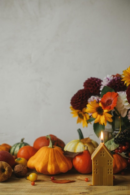 Buon Ringraziamento Zucche alla moda fiori autunnali bacche foglie candela sul tavolo rustico