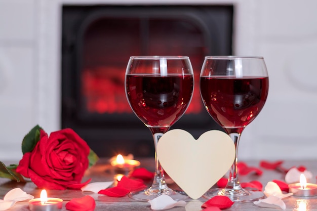 Buon San Valentino ci sono due bicchieri di vino rosso con un cuore di petali di rosa e candele