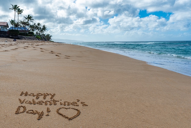 Buon San Valentino con un cuore disegnato nella sabbia sulla spiaggia