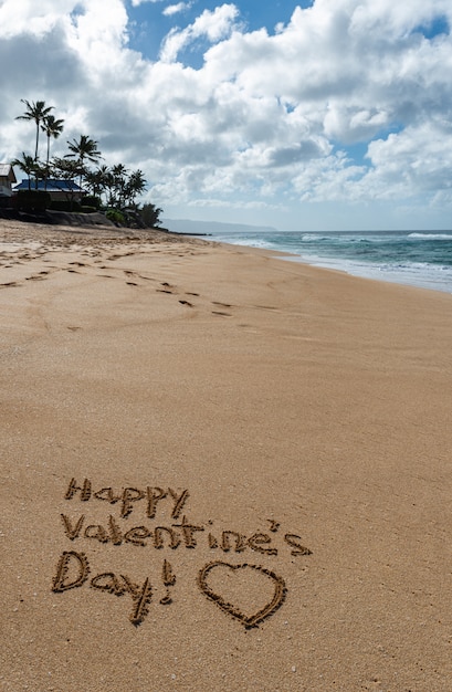 Buon San Valentino con un cuore disegnato nella sabbia sulla spiaggia