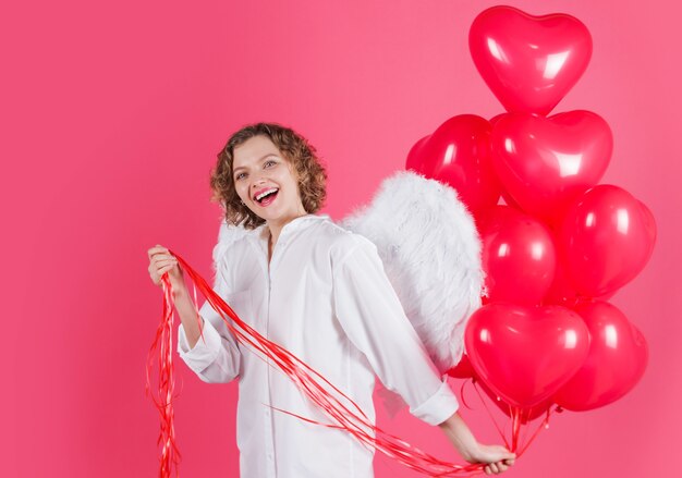 Buon San Valentino. Donna angelo con palloncini a forma di cuore rosso. Cupido femminile sorridente con le ali.