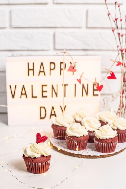 Buon San Valentino è scritto su una lampada decorativa accanto a cupcakes rossi