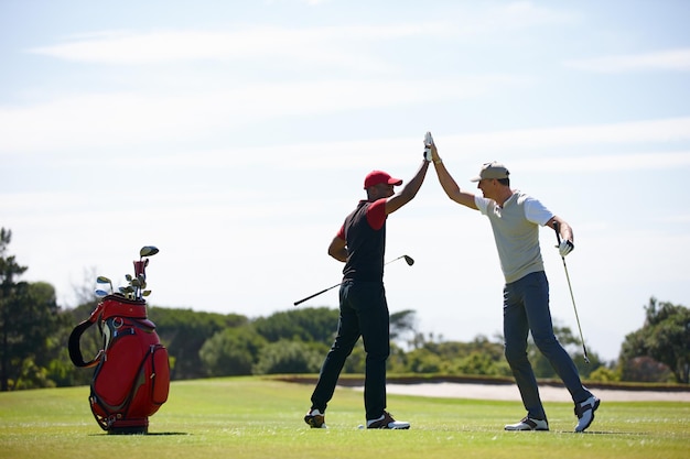 Buon tiro amico Inquadratura di due uomini felici che giocano a golf