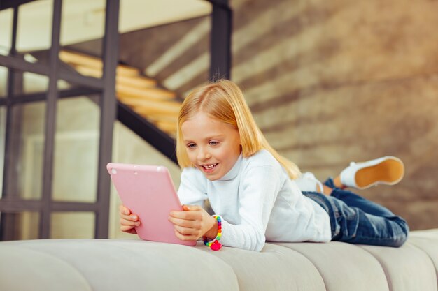 Buon umore. Bionda carina che sorride mentre usa il tablet her