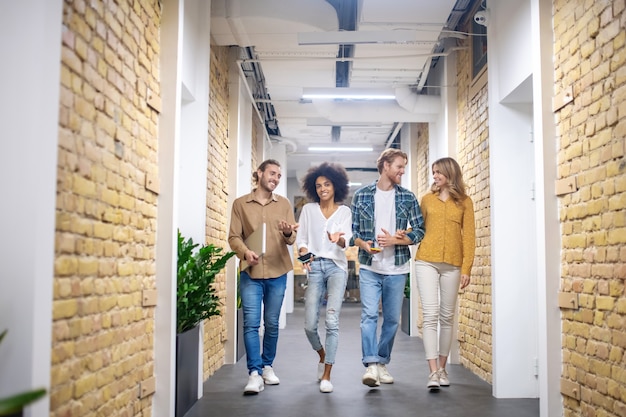 Buon umore. Gruppo di giovani sorridenti che camminano nel corridoio