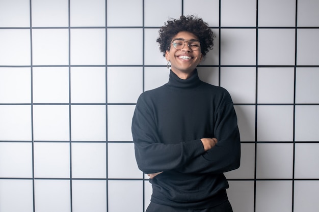 Buon umore. Ragazzo giovane afroamericano che indossa vestiti neri che si sente bene