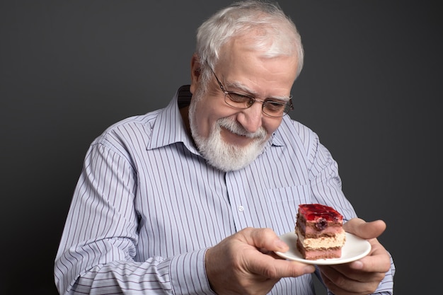 Buon uomo sorridente che tiene un piatto e guardando la torta