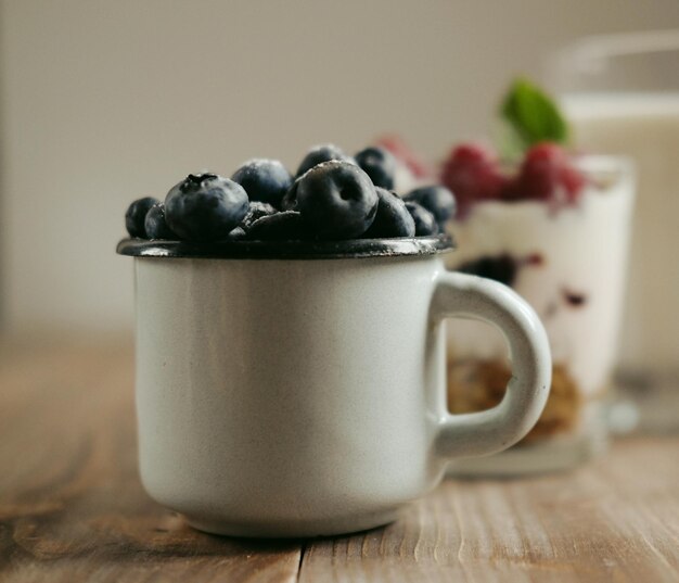 Buona colazione Una piccola tazza con i mirtilli un bicchiere di latte a