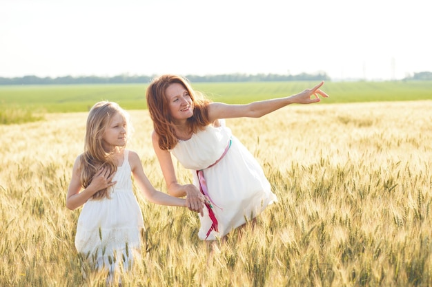 Buona estate e vacanze. Famiglia - madre con sua figlia che si tengono per mano in un campo di grano