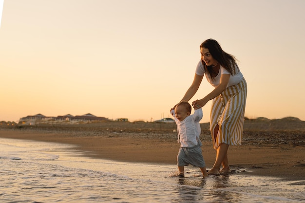 Buona festa della mamma Bella madre e bambino giocano sulla spiaggia La mamma e il suo bambino insieme si godono il tramonto Amare la madre single abbraccia il figlioletto carino