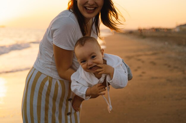 Buona festa della mamma Bella madre e bambino giocano sulla spiaggia Mamma e suo figlio insieme si godono il tramonto Amare la madre single abbraccia il figlioletto carino